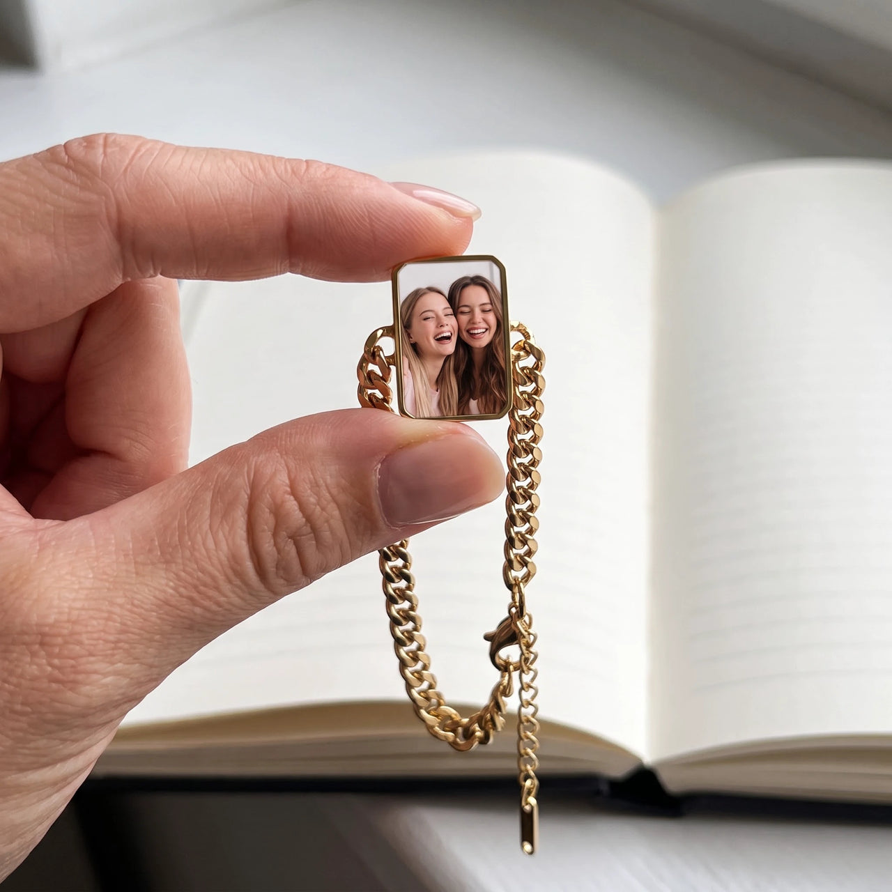 The gold cushion-cut photo charm held between two fingers, showing its real small size with a photo of two best friends laughing together | SKU: TPH-CUSB-GOLD