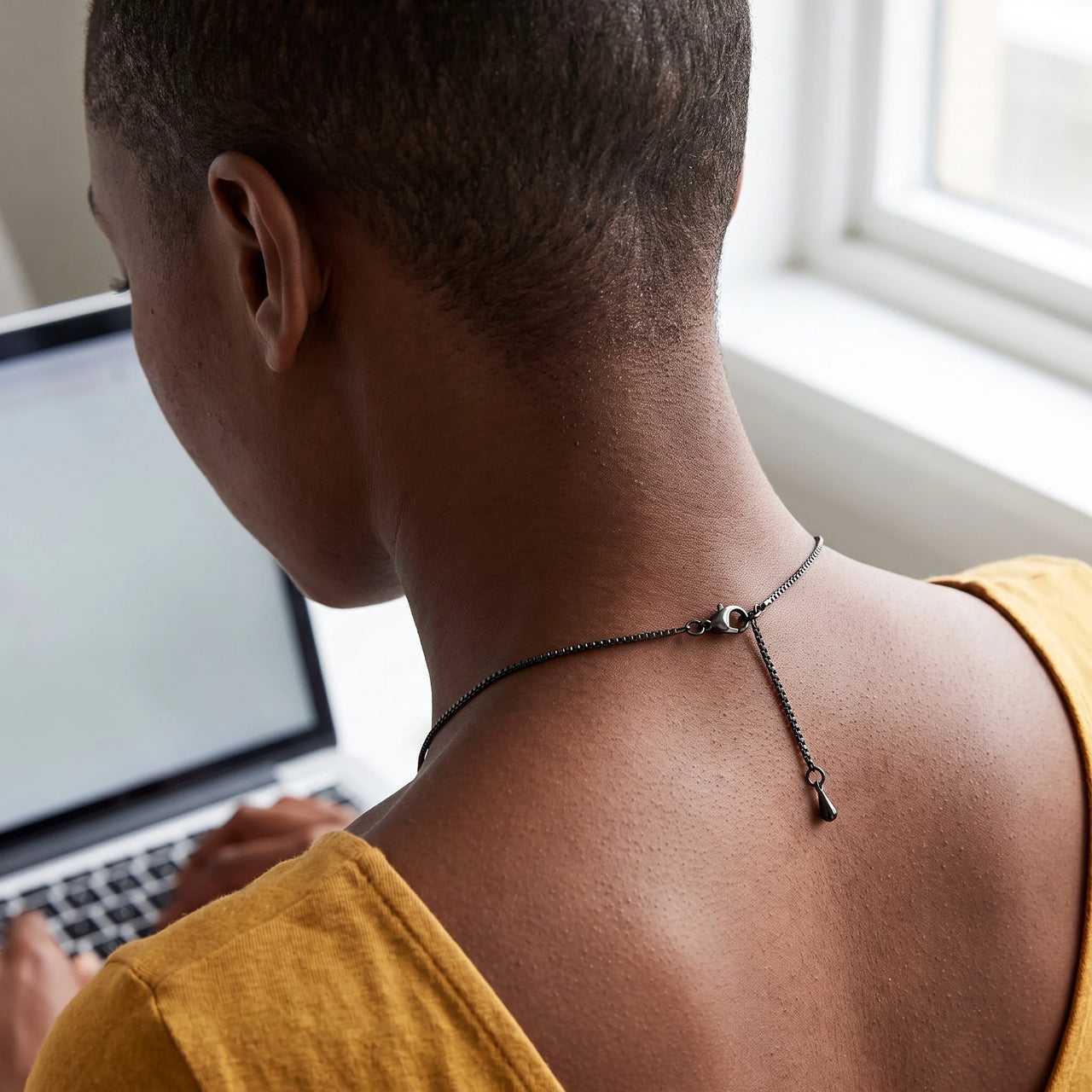 Back of the neck at a laptop desk showing the clasp and extension chain of the black drop photo necklace | SKU: TPH-DRPN-BLACK