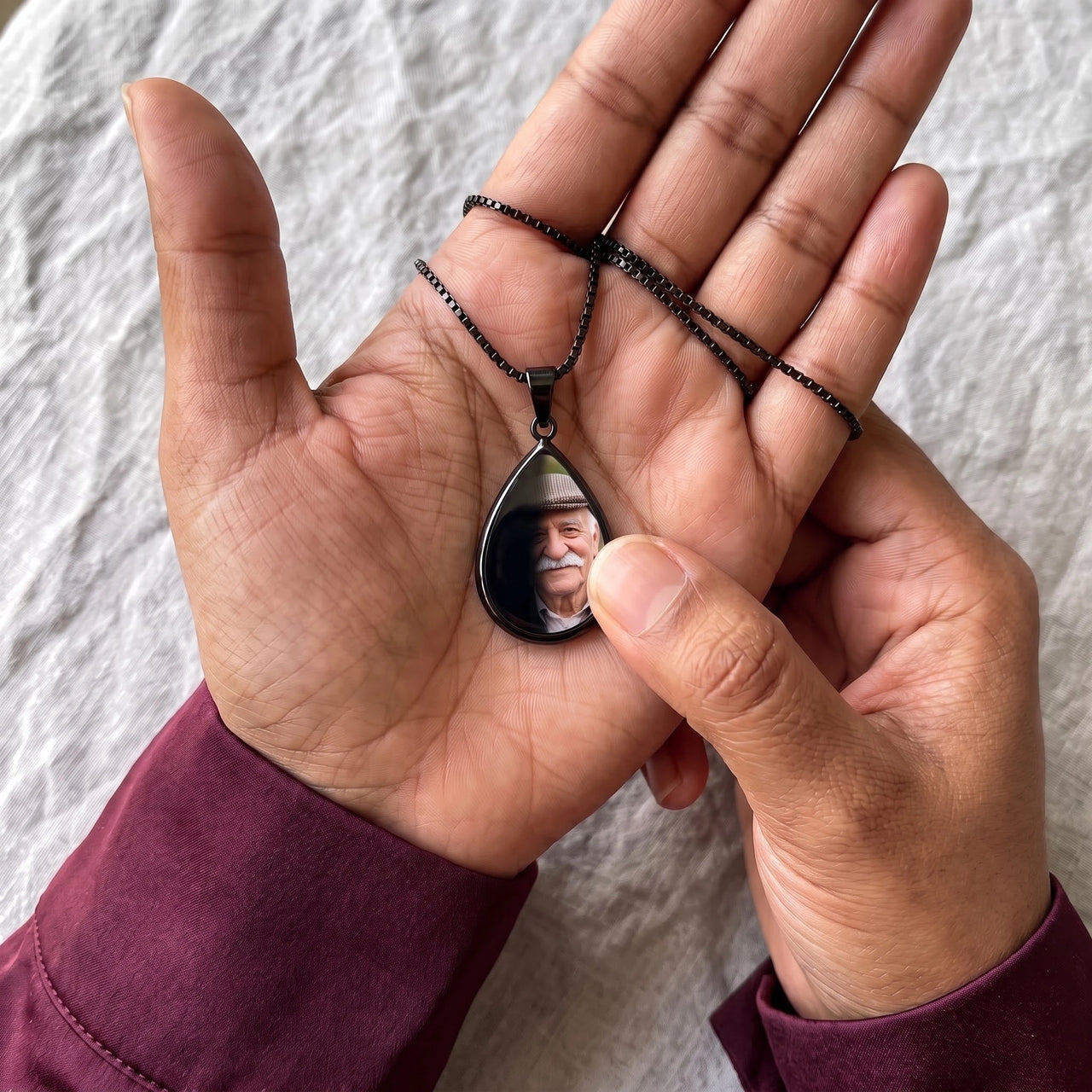 Thumb warming the black teardrop pendant: the hidden photo appears under the thumb while the rest stays black | SKU: TPH-DRPN-BLACK