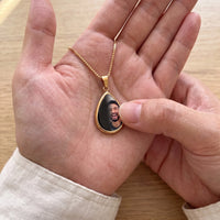 Thumbnail for Thumb warming the gold teardrop pendant: the hidden photo appears under the thumb while the rest stays black | SKU: TPH-DRPN-GOLD