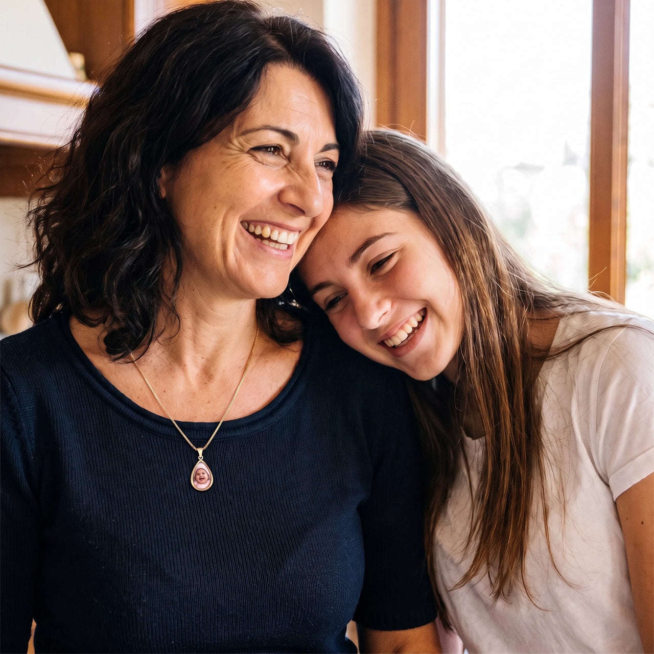 Mother and teenage daughter hugging and laughing, the mother wearing the gold secret drop photo necklace | SKU: TPH-DRPN-GOLD