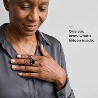 Thumbnail for Woman holding the black teardrop pendant on its silver chain against her chest, only she knows the photo inside | SKU: TPH-DRPN-SILVER